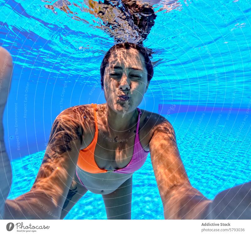 Woman enjoying underwater selfie in sunny pool woman swimming summer blue playful fun swimwear bikini leisure aquatic vacation holiday sunshine ray light
