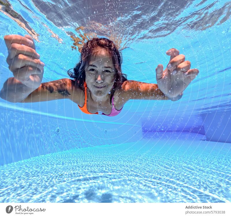 Underwater View of a Woman Swimming in a Pool woman underwater swimming pool clear blue serene smile reaching camera submerged swimwear leisure activity summer