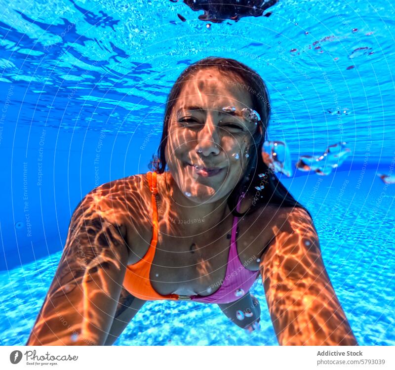 Underwater fun with a smiling woman swimming at the beach underwater sunny light pattern cheerful blue ocean sea summer vacation leisure activity swimwear