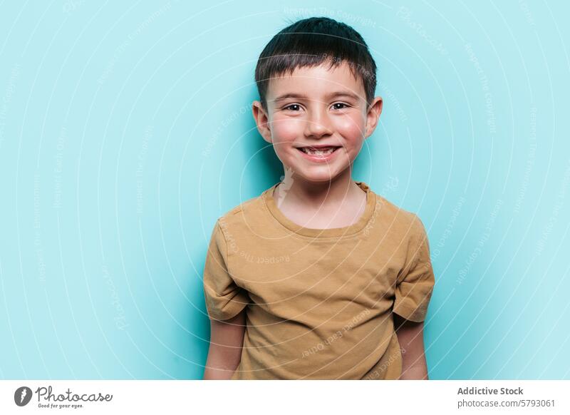 Cheerful boy smiling in a studio setting child portrait happy joy blue background innocence male kid cheerful expression positive youth shirt casual teal fun