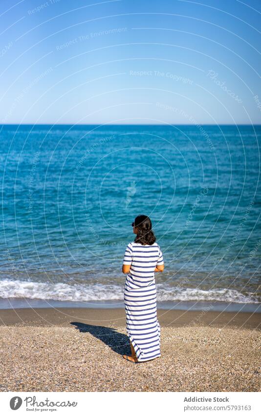 Woman gazing at the sea in Sardinia woman sardinia italy beach mediterranean water coast clear pebble dress striped blue horizon summer travel ocean sky