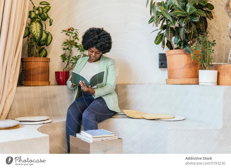 Woman reading in a modern coworking space woman book african american plant stylish furniture well-lit focus indoor seated professional comfort tranquil serene