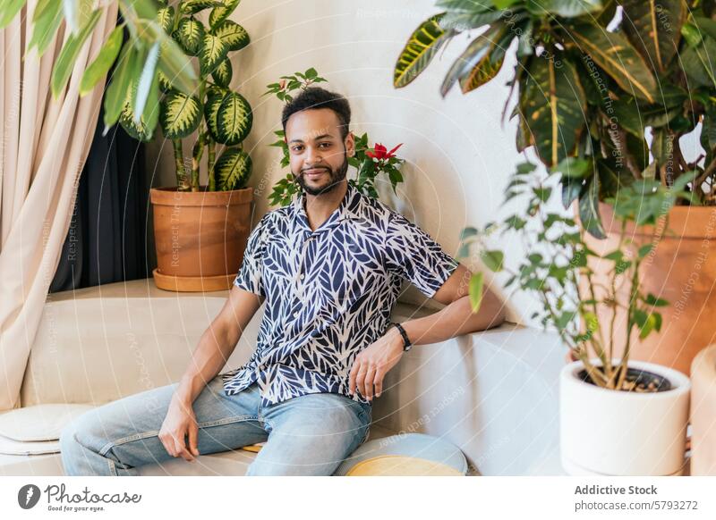 Relaxed man enjoying a break in a plant-filled coworking space indoor relaxation creativity couch casual clothing young adult male lounge comfort bright vibrant