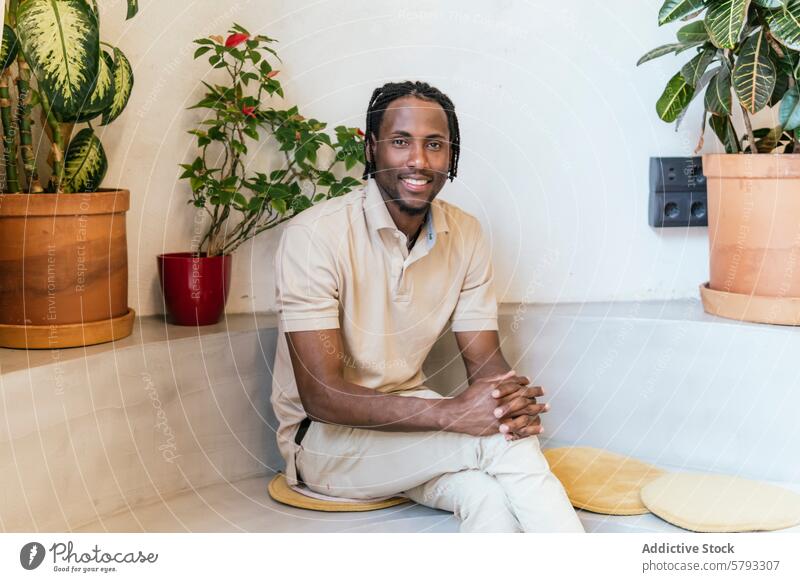 Relaxed entrepreneur at a plant-filled coworking space cowoorking ethnic african american black man smiling plants indoor modern relaxed office casual sitting