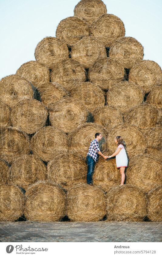 a guy with a girl on a summer walk in the field round haystack dry yellow dress shirt cage drawing pattern warehouse mountain sunset evening village farmer