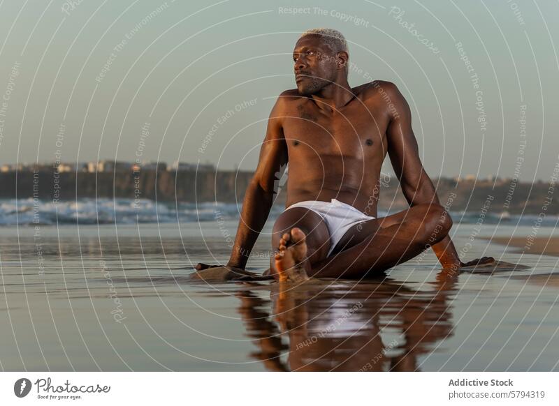 Pensive African American man sitting on beach at sunset model african american black reflection tranquil shore ethnicity contemplative posing water evening dusk