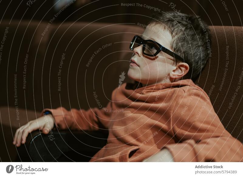 Boy in glasses watching movie during summer boy indoors sofa leisure activity seated child young screen entertainment film 3d glasses living room absorbed
