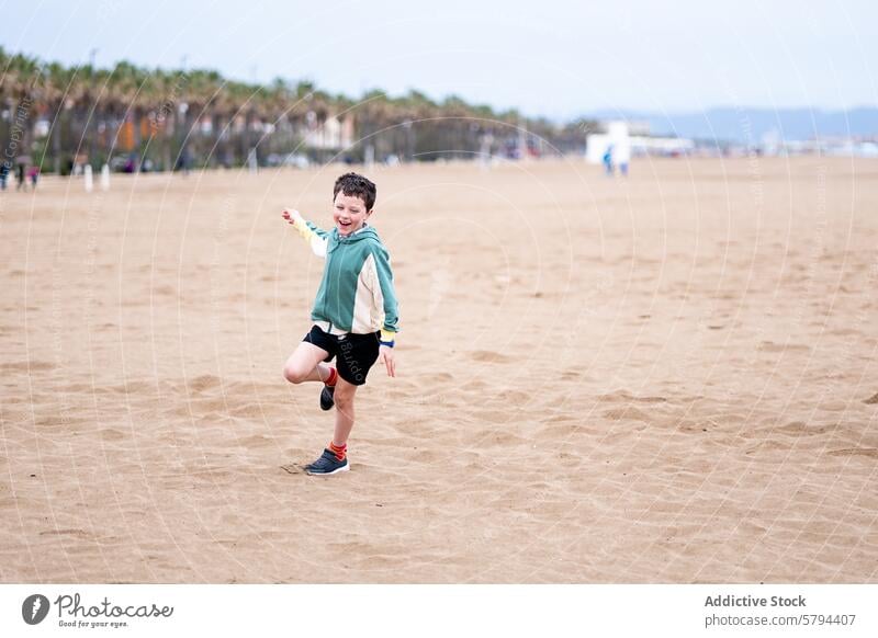 Young boy playing joyfully on the beach during summer child sand happy vacation leisure outdoor palm tree coast seaside ocean fun smile young kid youth playful