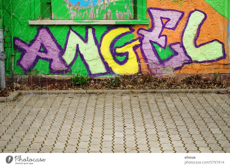 Colorful graffiti on a house wall with the lettering ANGEL angel Angel Graffiti variegated English house facade Youth culture spray Street art Guardian angel