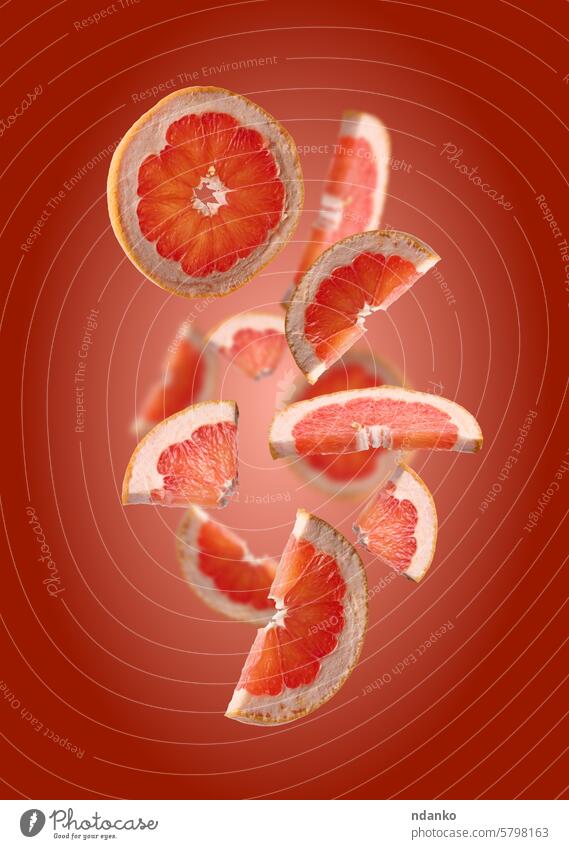 Various pieces of ripe grapefruit on a red background juicy circle citrus cut food fresh no people orange raw slice sweet vegetarian vitamin set levitation