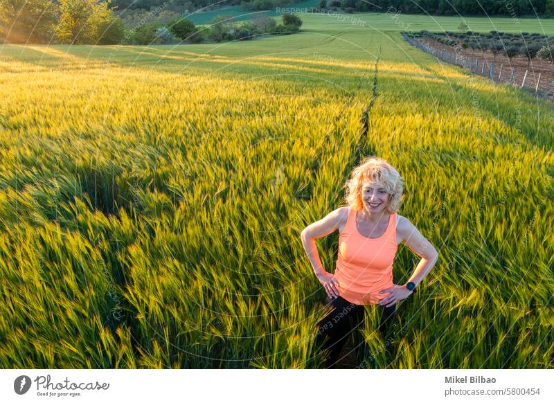 young caucasian mature woman  inside a barley field at sunset.  Ayegui, Navarre, Spain, Europe. Lifestyle concept. people nature girl countryside green