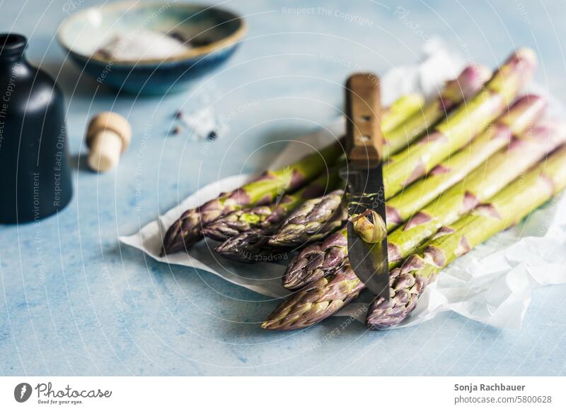 Green asparagus and a knife on a light blue table. Spring, vegetables. Asparagus Fresh Raw Knives peel Vegetable Vegetarian diet Food Diet Organic produce