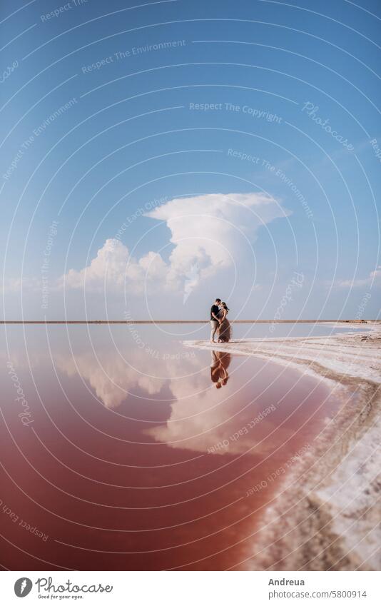 girl and a guy on the shore of a pink salt lake young couple stand reflection style together beach sea river white lilac sky light blue nature landscape