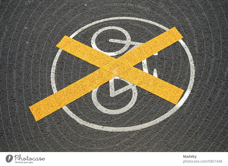 Yellow crossed white marking with white painted traffic sign on the gray asphalt of a cycle path in the city center of the trade fair city of Leipzig in the Free State of Saxony