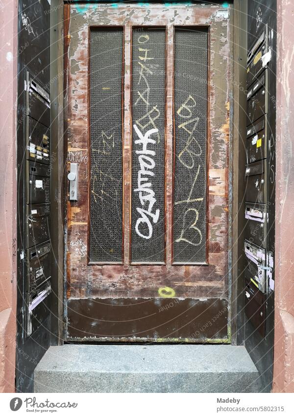 Old brown wooden front door with ribbed glass and graffiti on the test specimen in the Bornheim district of Frankfurt am Main Solid sure Safety Screening