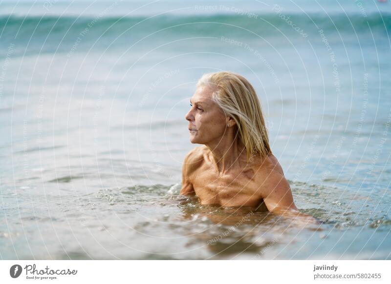 Eldery woman in good shape bathing in the sea. mature beach swim active swimming senior old water person summer nature vacation female lifestyle healthy