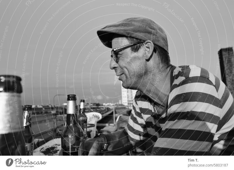 Man with hat, glasses, beer b/w Eyeglasses Smiling side view Beer Terrace Roof Treptow Berlin Black & white photo Day Exterior shot Town Capital city Downtown