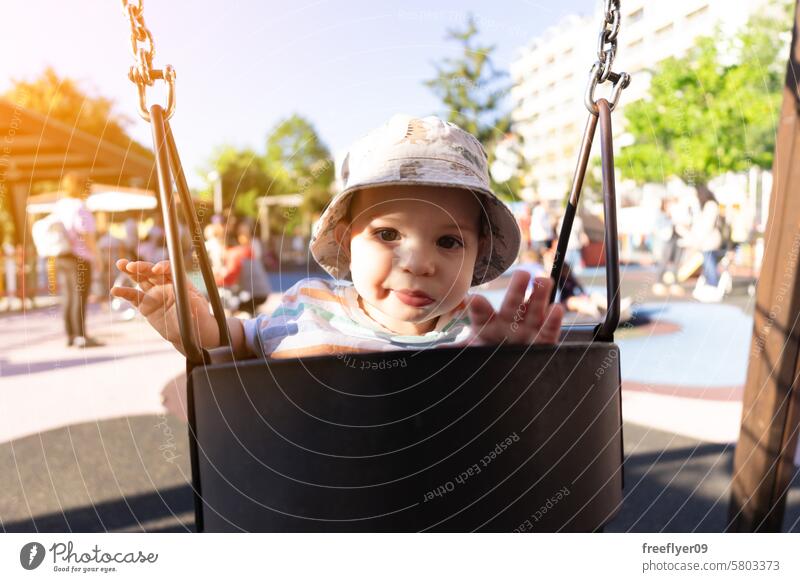 Portrait of a nine month old baby having fun on a swing toddler park happiness funny happy boy play school preschool recreation day care cheerful spring