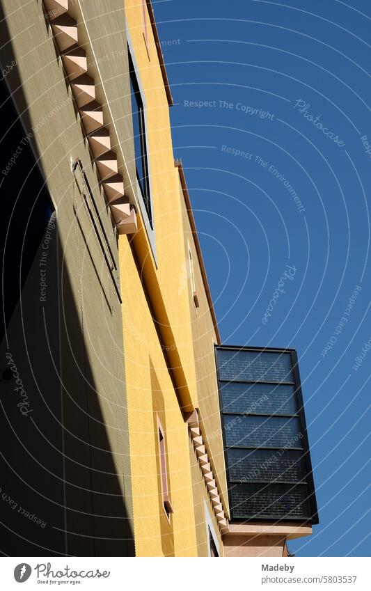 Geometric architectural accents in a modern façade in yellow and beige against a blue sky in the sunshine as part of the Goethehöfe on Großer Hirschgraben in the city center of Frankfurt am Main in Hesse