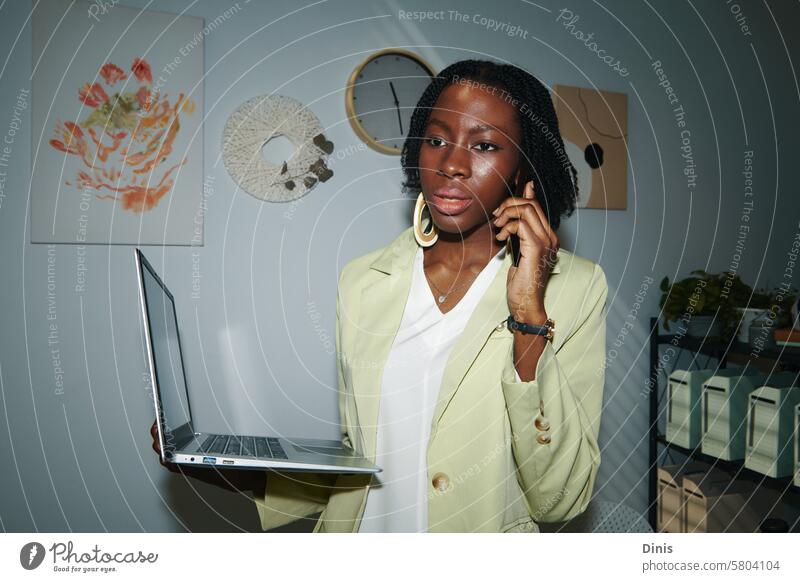 Portrait of serious Black entrepreneur with laptop talking on phone with colleague Black woman call Online email check Computer businesswoman career startupper