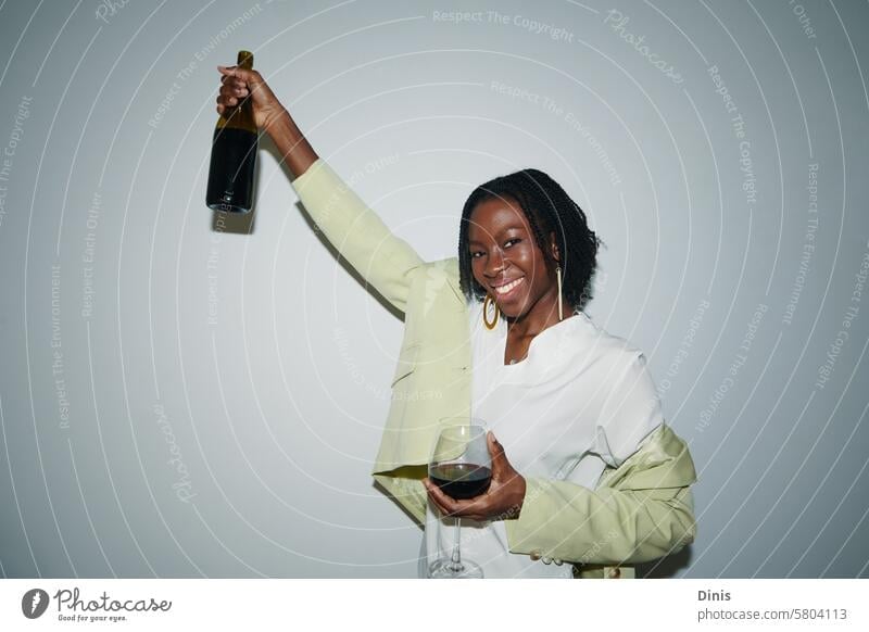 Portrait of young Black woman having bottle of red wine on Friday night celebration promotion drink Party portrait office celebrate businesswoman workplace
