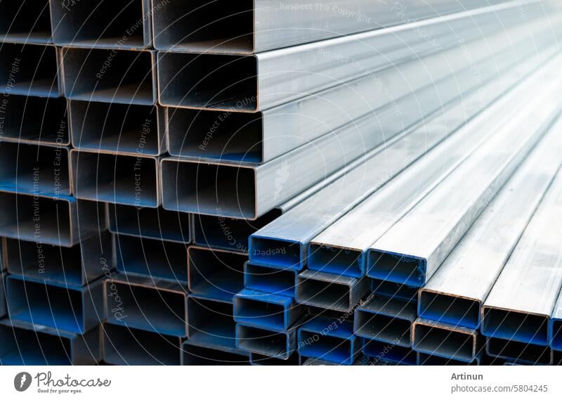 Industrial warehouse stock of rectangular metal pipes for building and construction supplies. Stack of steel pipes. Iron materials for construction and infrastructure projects. Steel tubing storage.
