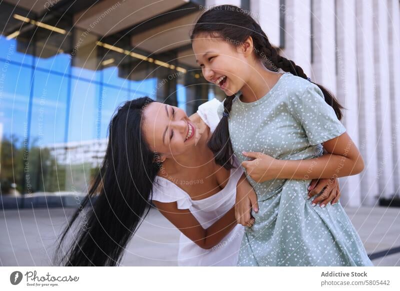 Embrace Between Mother and Daughter with autism spectrum mother daughter laughing together joyful embrace playful love modern building outdoor happiness family