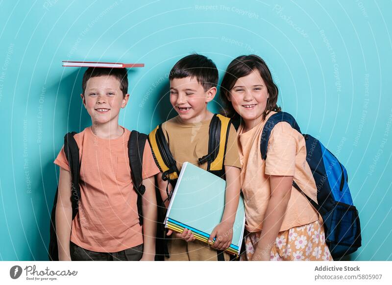 Happy school kids with backpacks and books children boys girl smile education turquoise background cheerful friendship balance head happy looking at camera