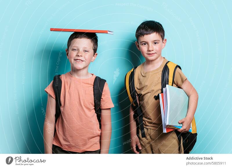 School Boys Ready for Class with Books and Backpacks school boy backpack smile camera teal background book head standing education young child pupil student