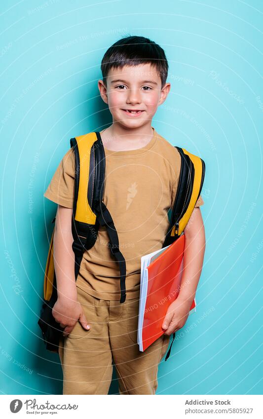 Happy school boy ready for class with backpack and notebook student smiling education smile happy youth learning standing blue background portrait child
