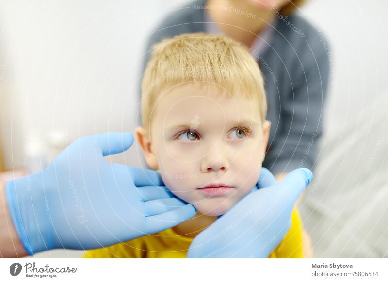 A cute toddler boy with his mother are at an appointment with a pediatrician. The doctor ENT is examines lymph nodes of a little patient. child kid test