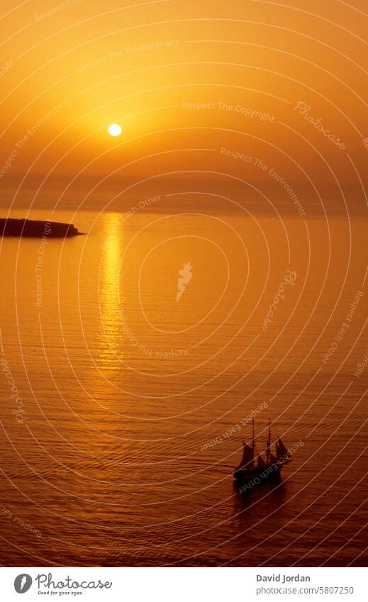 orange golden sunset with sailing ship in the Mediterranean Sea Sunset Orange Mediterranean sea Sailing ship before sunset Greece Santorini