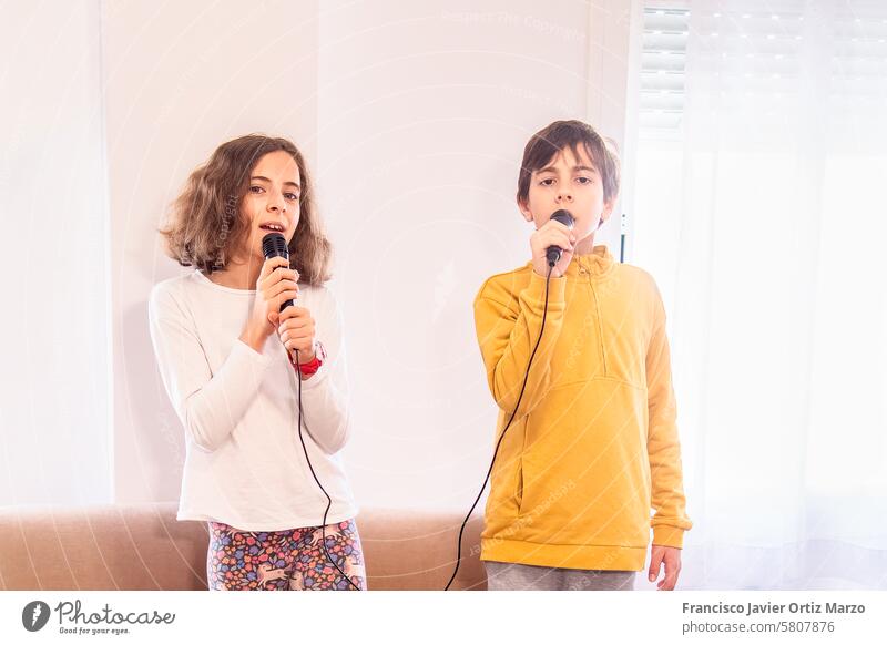Children Singing into Microphones Together two child singing microphone performance music passion entertainment fun expression talent vocalist duet joy cord