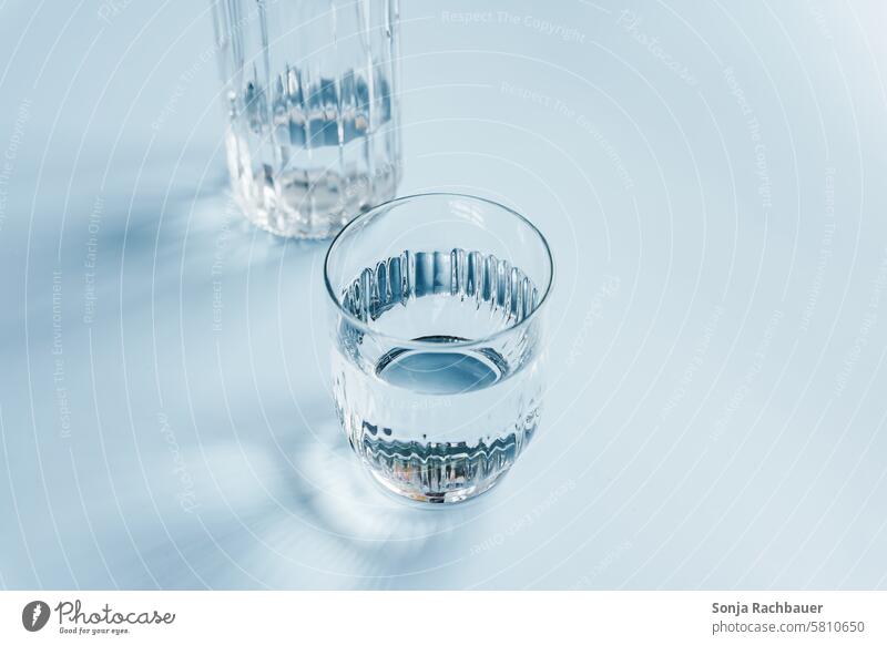 A glass of water and a carafe on a blue table Water drinking glass Blue Drop shadow Tumbler Drinking water Beverage Cold drink Mineral water Refreshment Fluid