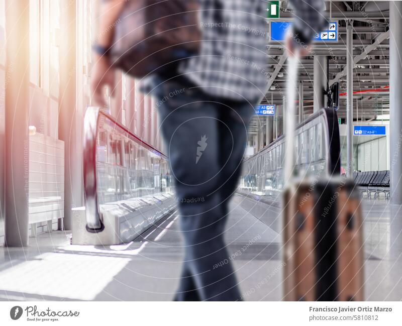 Unfocused photo of unrecognizable man walking with suitcase in airport terminal unfocused travel walkway escalator aircraft flight departure vacation trolley