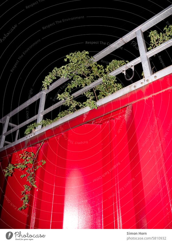 Solid, red steel construction with railing through which a green plant grows Steel construction Fastening Massive stable Red Overgrown Construction Architecture