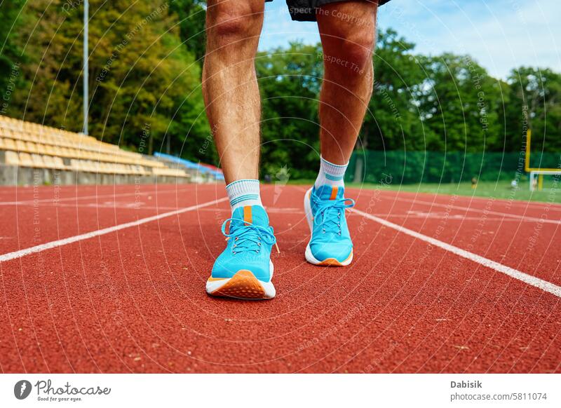 Athlete Wearing Bright Blue Running Shoes on Red Stadium Track During Training running shoes track stadium training exercise athletic blue sneakers sports legs