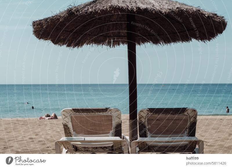 Shady spot with two loungers on the beach and sea view Sunshade sun protection Summer Lie Sun loungers beach couch Sunbathing Shadow shaded place Blue sky