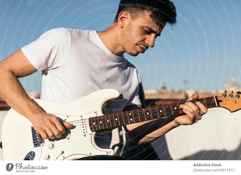 man playing electric guitar on a rooftop instrument musical guitarist musician sound guy black acoustic performer studio clouds sky player male concert band