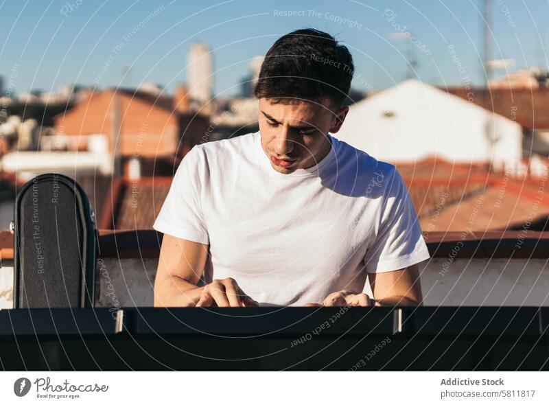 Front view of a man playing music keyboard on a rooftop instrument piano city person black outdoors musician sound pianist white player caucasian closeup finger