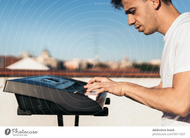 man playing piano on an urban rooftop instrument music city person black outdoors musician sound pianist key white player caucasian closeup finger hand concert