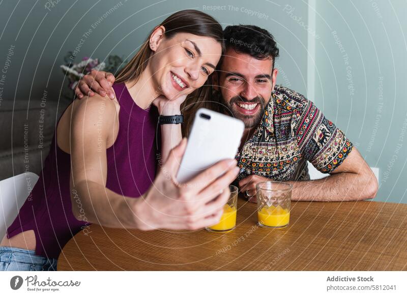 Smiling couple taking selfie in kitchen smartphone happy toothy smile hug together friend self portrait memory take photo positive young using social media