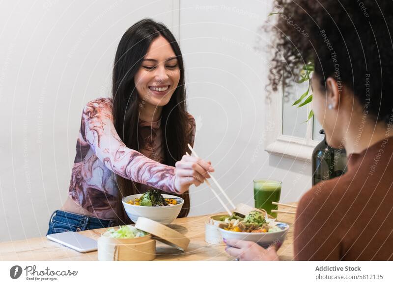 Delighted friendly multiethnic women eating in restaurant chill poke dish tasty friendship together diverse multiracial black african american female enjoy
