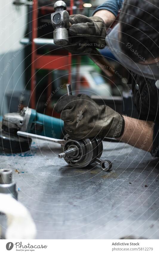 Anonymous repairman fixing motorbike crankshaft bearing in workshop assemble hammer mechanic auto garage job tool male goggles glove manual professional service