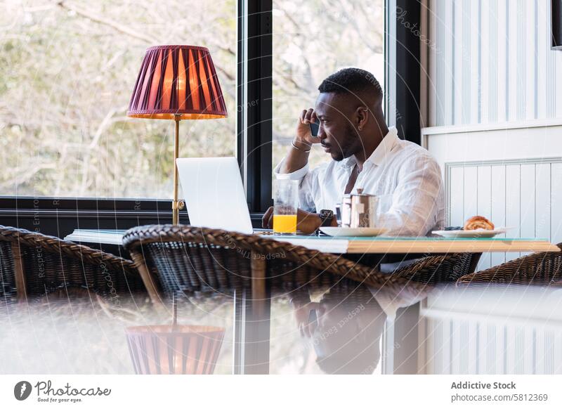 Black man talking on phone in cafe discuss serious busy breakfast call conversation adult businessman african american black ethnic laptop gadget device