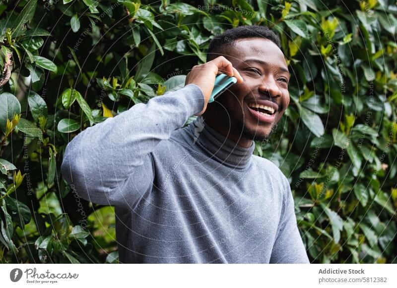 Cheerful black man talking on smartphone in park happy conversation cheerful laugh mobile male young african american ethnic phone call lifestyle speak optimist