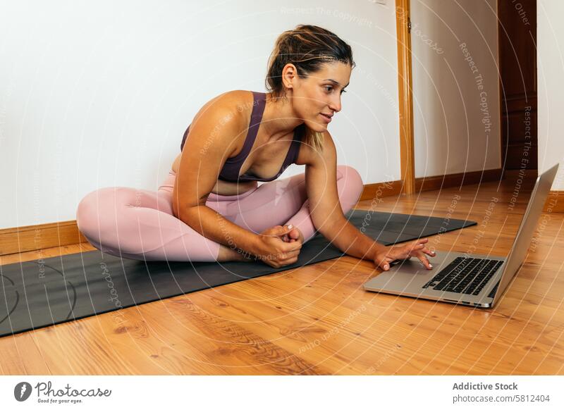 woman in sportswear doing yoga with laptop at home healthy exercise lifestyle fitness body workout caucasian training pilates young floor wellness activity