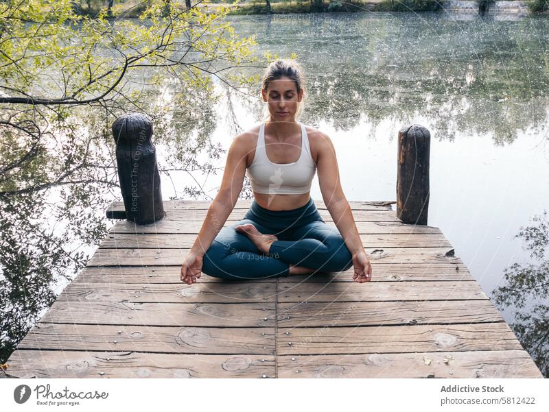 woman meditating in nature near a lake yoga meditation healthy relaxation body adult pose lifestyle balance exercise young person concentration zen peaceful fit