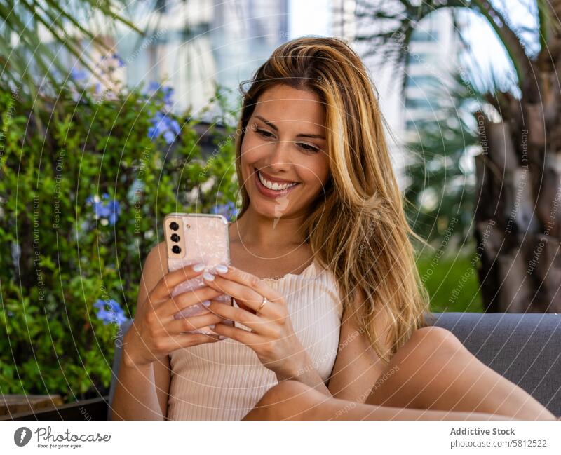 Close-up of a beautiful woman sitting on a sofa while writting a message on her smartphone. Beautiful People adult alone attractive browsing cell cellphone