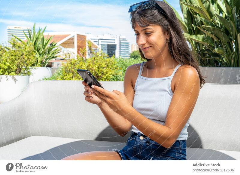 A woman iis looking at her smartphone outdoors. Modern adult app attractive beautiful browsing business casual caucasian cell cellphone city communication